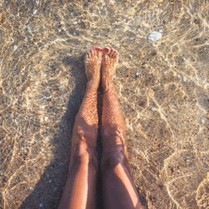women sitting in the sand and water at the beach